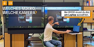 Michael Zgoll demonstriert BYOD vor einer Wand mit zwei Displays